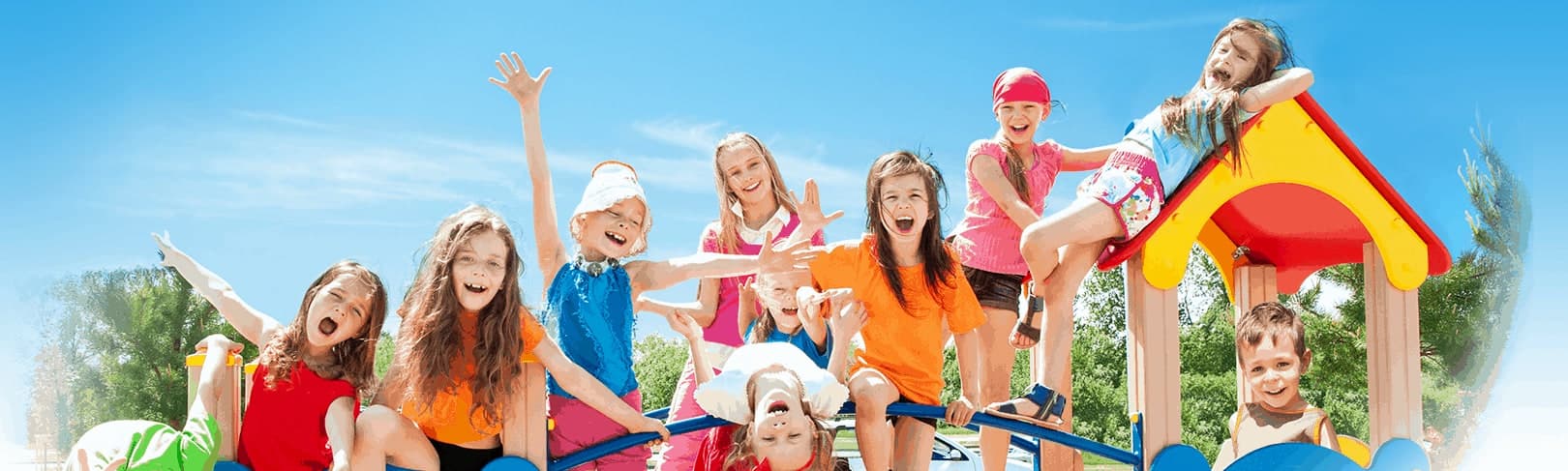 Group of happy, laughing children playing on a colorful playground under a blue sky